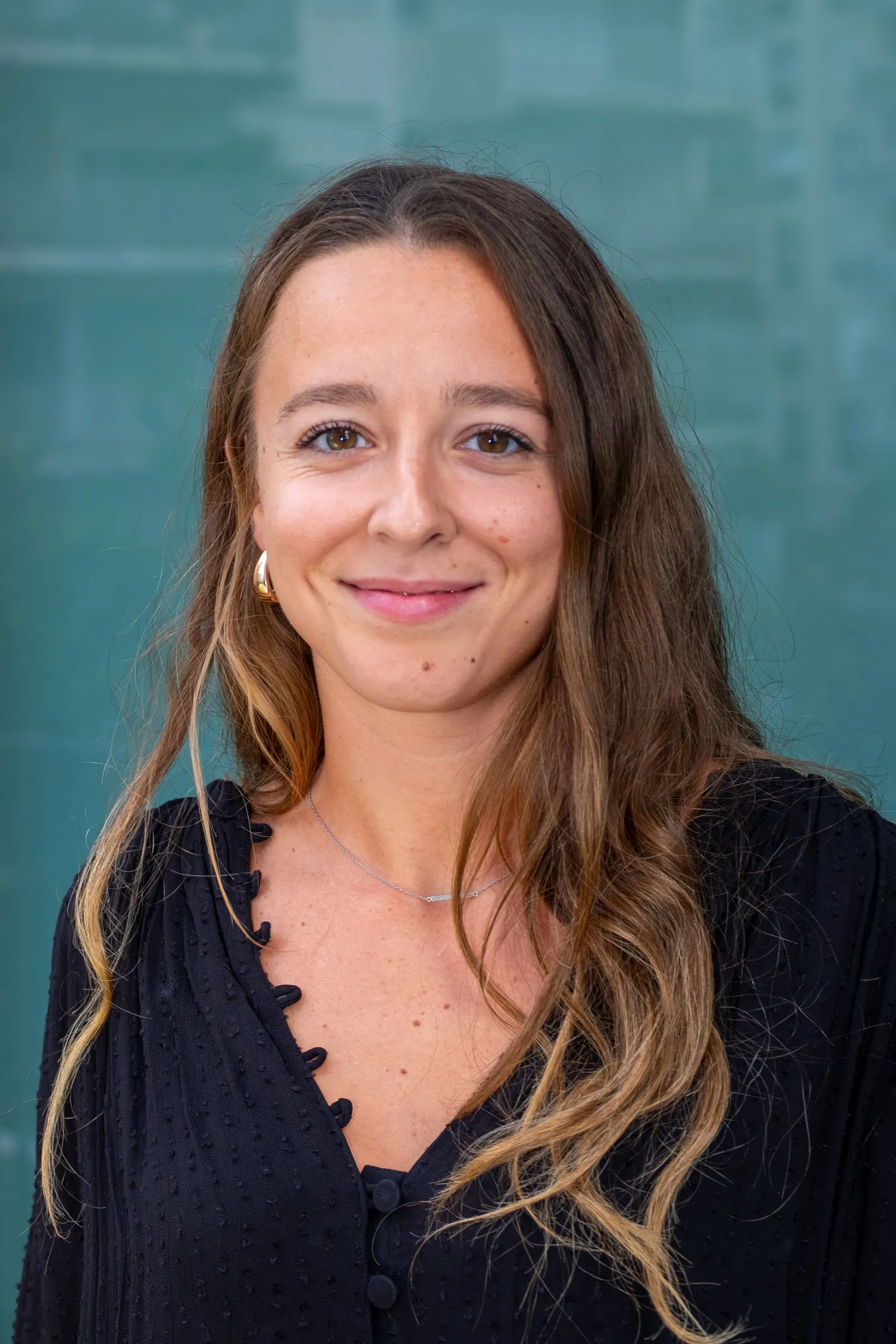 Portrait of a woman with long hair against a teal wall